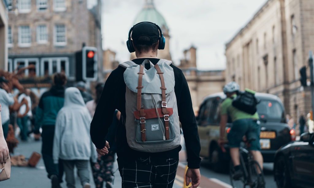 a man walking down the street wearing headphones