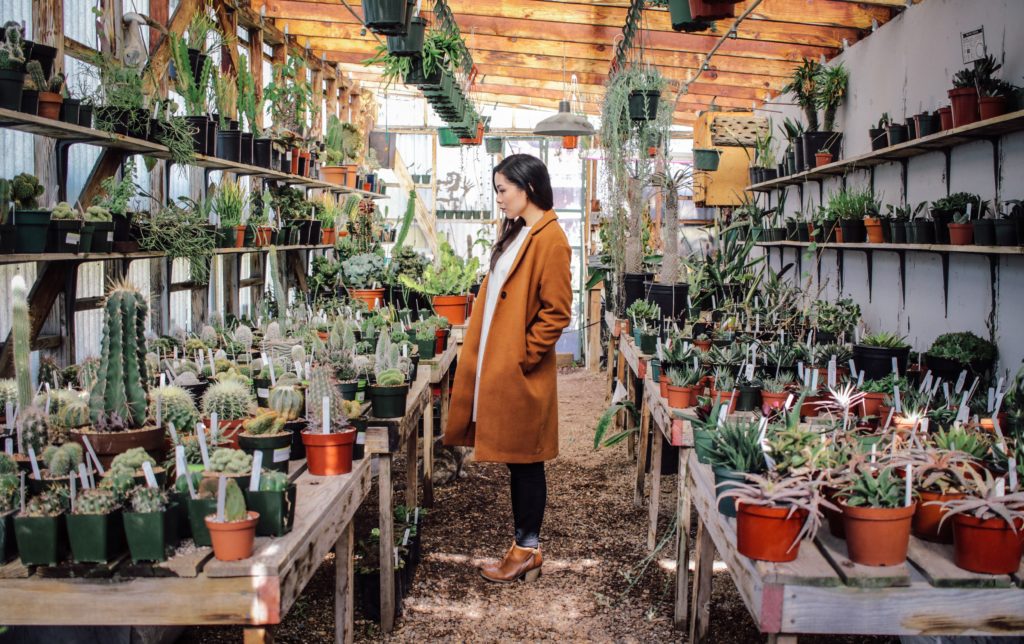 Woman in a nursery with an overwhelming selection of plants to choose from.