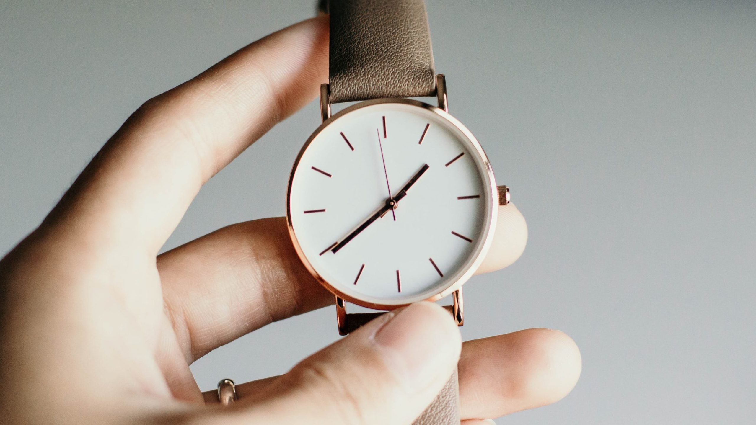 A hand holding a watch, tracking the time.