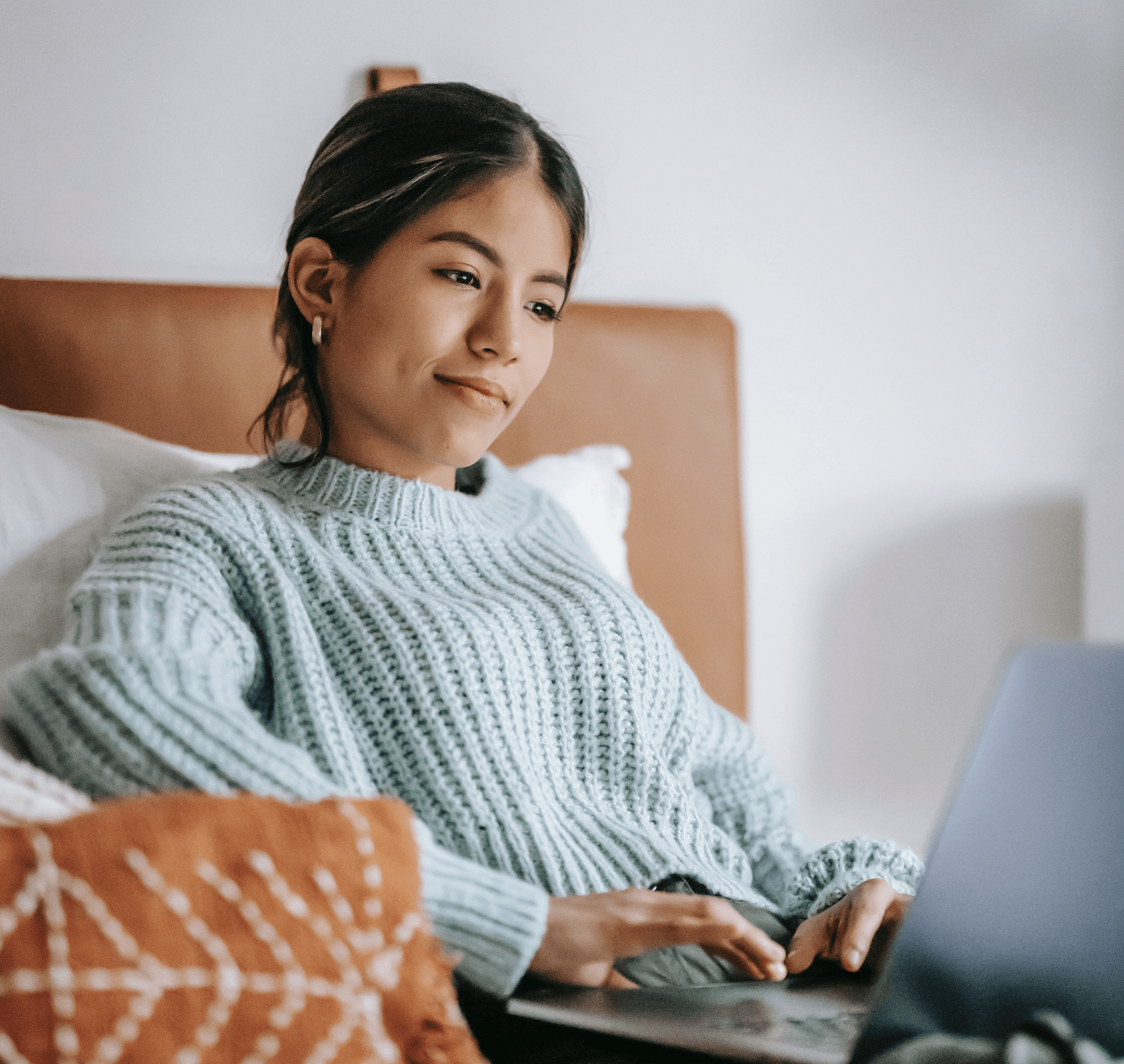 woman on a laptop in her bed running an online mentoring program