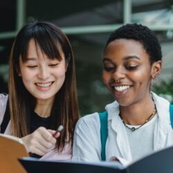 two women sharing notes from their notebooks