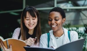 two women sharing notes from their notebooks